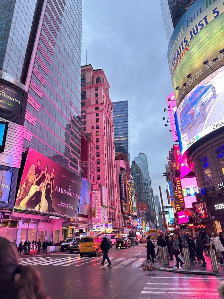 people crossing the street in times square at dusk