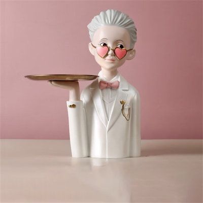 a white statue holding a tray with a pink heart on it's nose and wearing a suit