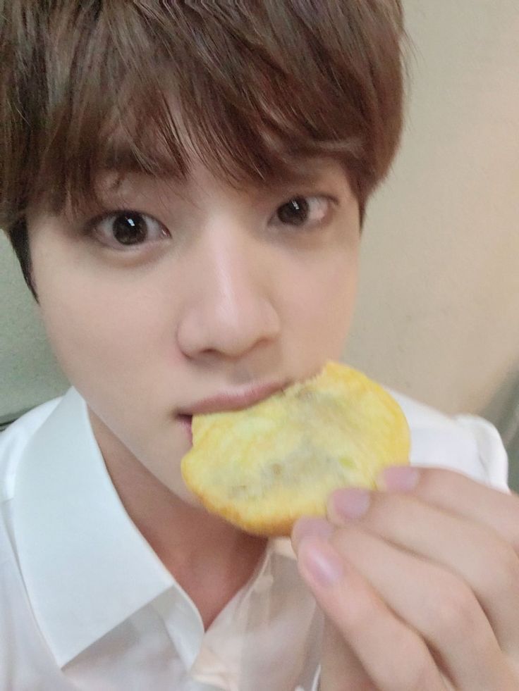 a young man is eating something with his hand