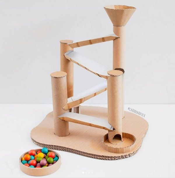 a toy made out of cardboard with candy in the foreground and a bowl of candies on the ground