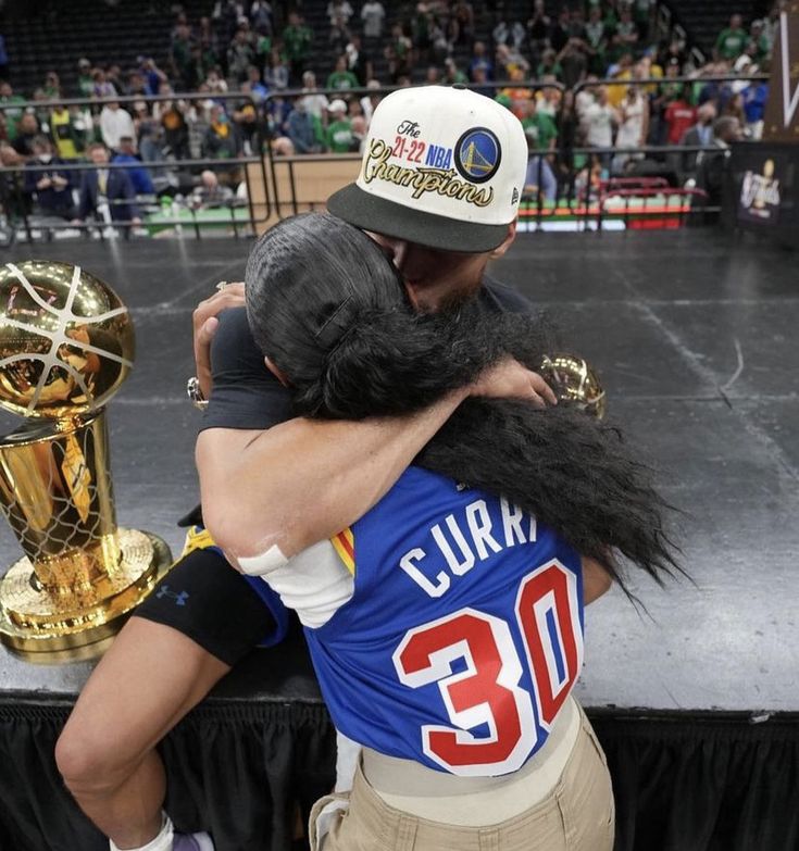 two people hugging each other in front of a stage with the trophy on it's back