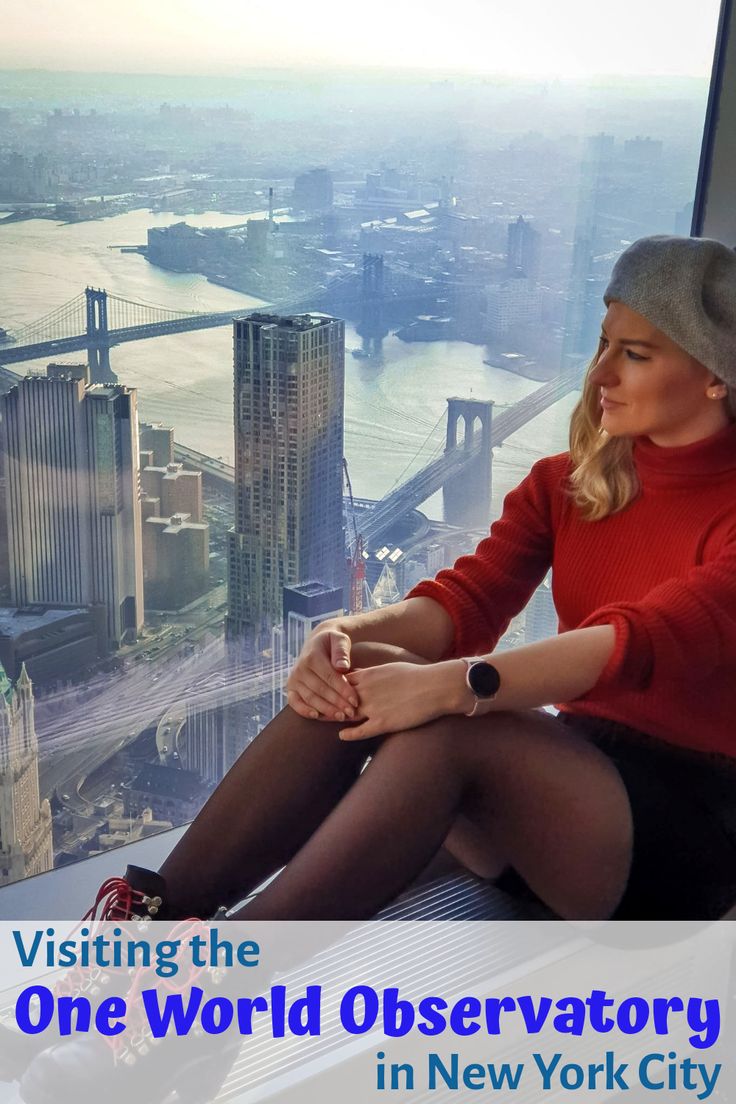 a woman sitting on top of a building looking out at the water and buildings in new york city