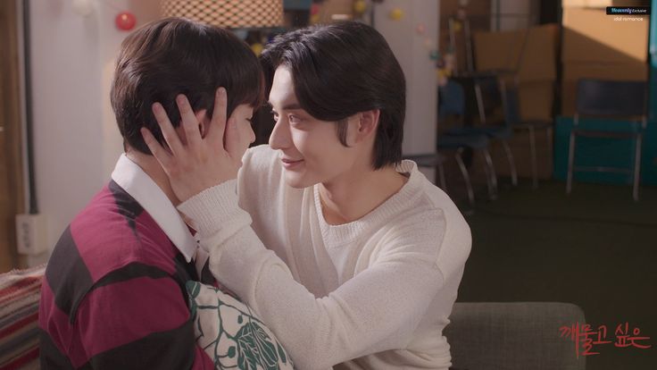 two young men sitting next to each other in front of a tv screen, one holding his head