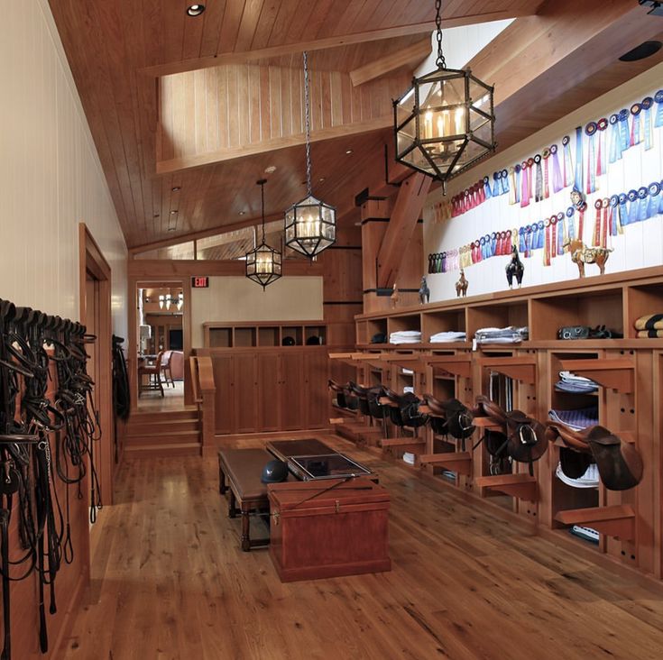 the inside of a horse shop with lots of saddles hanging from the ceiling and wooden shelves