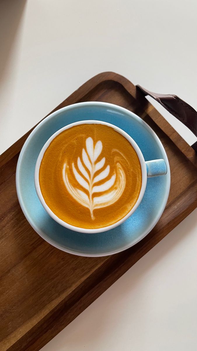 a cappuccino on a blue plate with a wooden serving tray and spoon