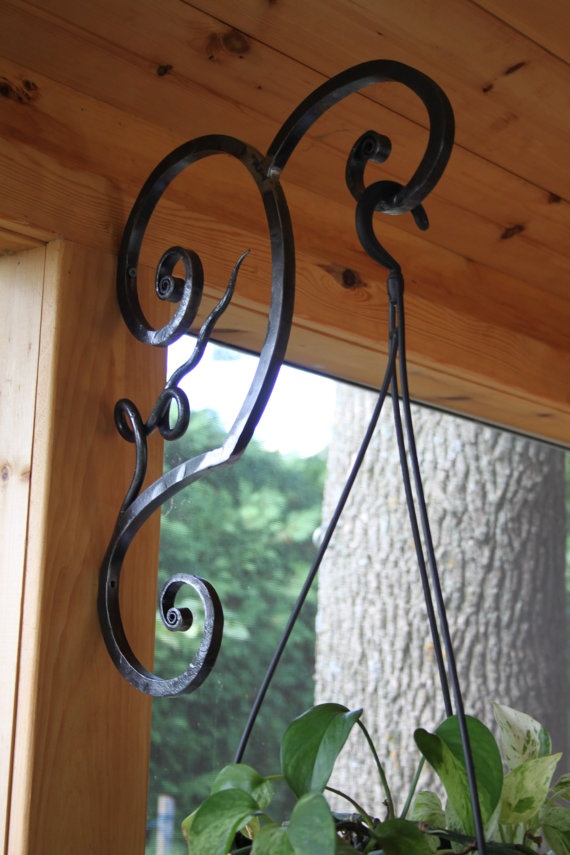 an iron plant hanger on the side of a window