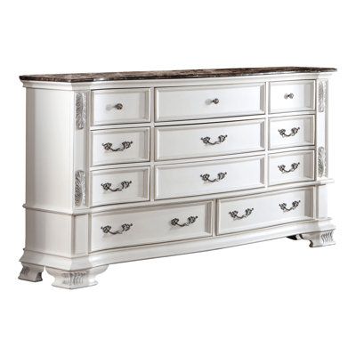 an antique white dresser with marble top and drawers on the bottom, against a white background