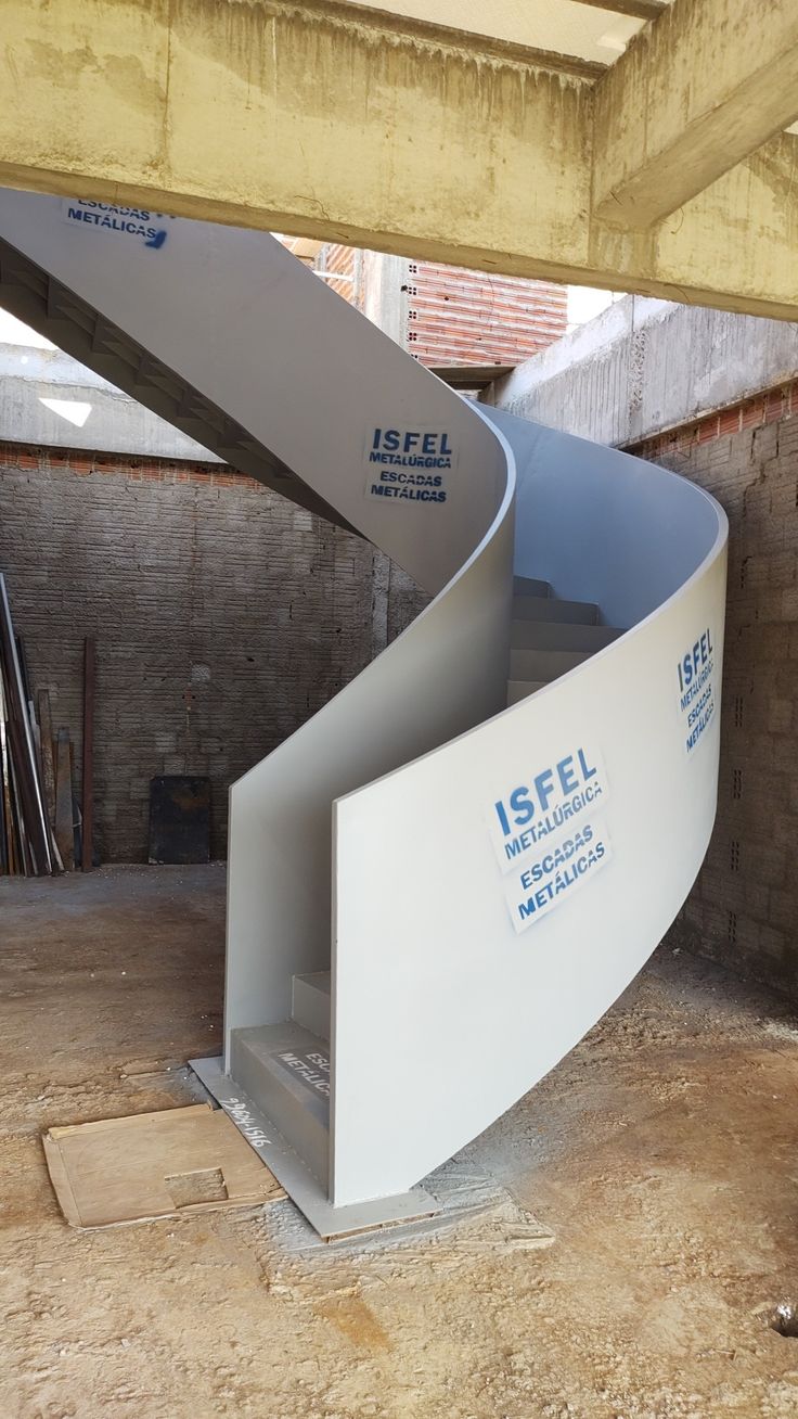 a curved metal staircase in the middle of a building under construction with brick walls and exposed ceilings