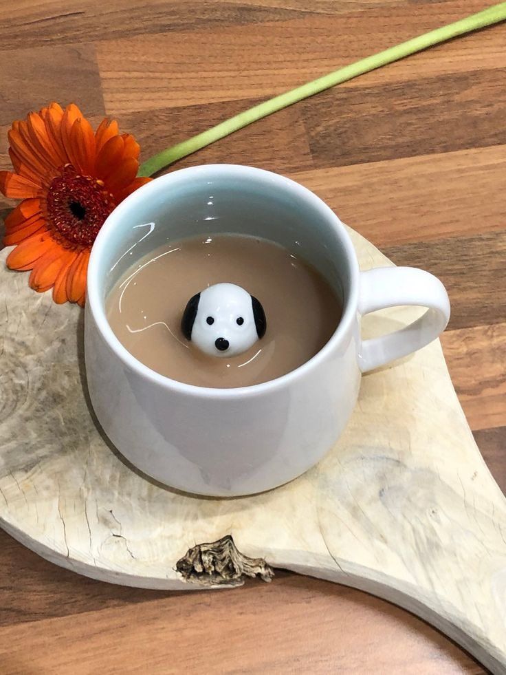 a white cup filled with liquid next to an orange flower