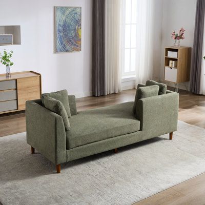 a living room scene with focus on the couch and chair in the foreground, along with an area rug