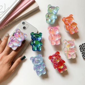 a person holding a cell phone next to many small bear shaped rings on a table