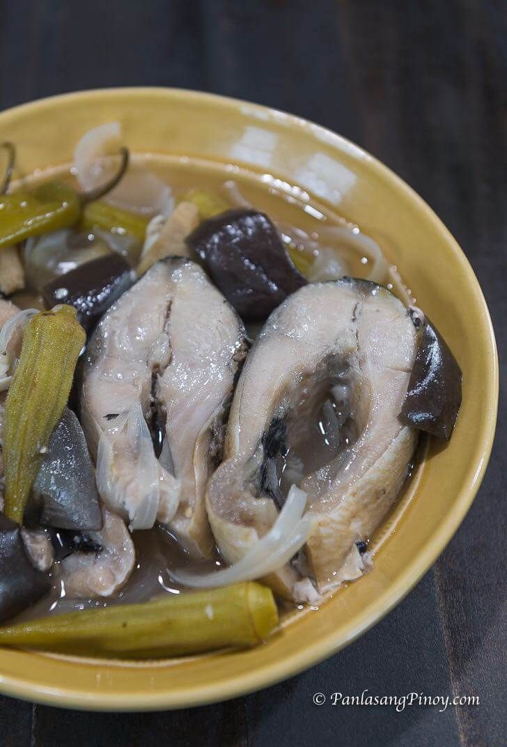 a yellow bowl filled with mushrooms and pickles on top of a black tablecloth