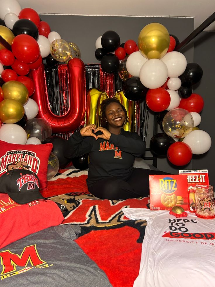 a woman sitting on top of a bed surrounded by balloons and other items in front of her