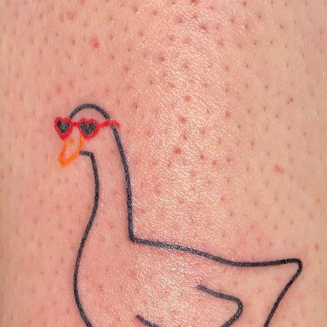 a close up of a person's arm with a duck tattoo on the side