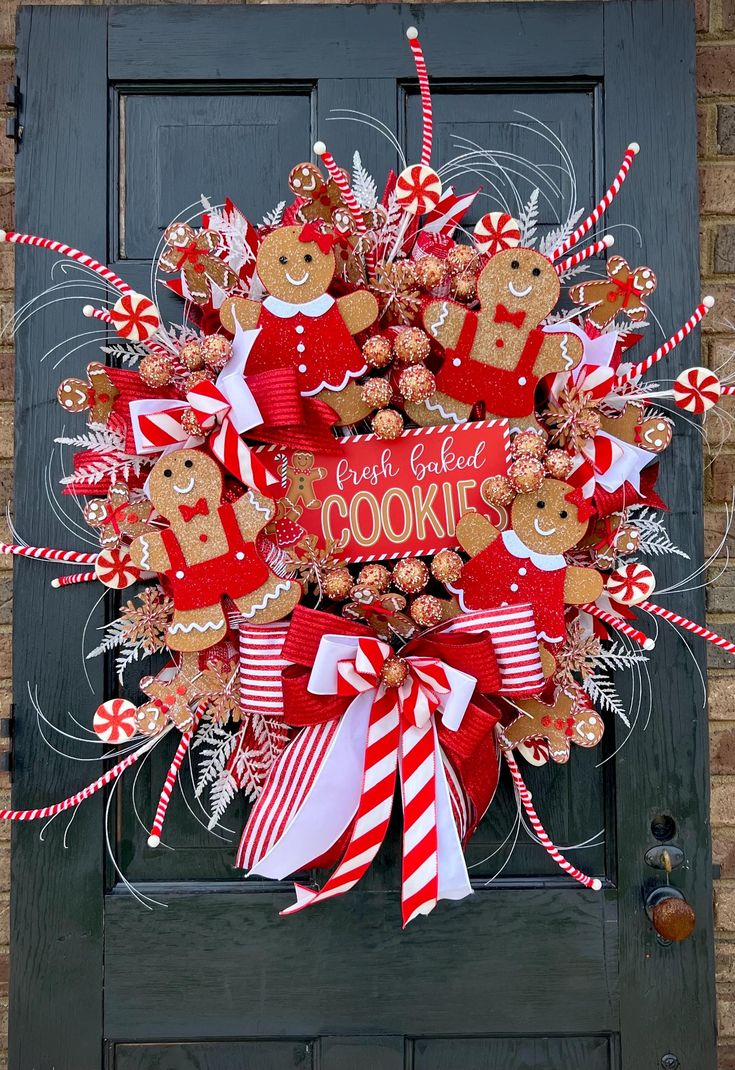 a wreath with gingerbread cookies and candy canes on the front door for christmas