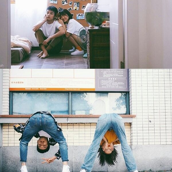 two people doing handstands in front of a building and another person sitting on the ground