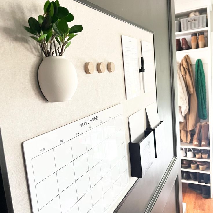 a wall mounted calendar board with shoes on it and a potted plant in the corner