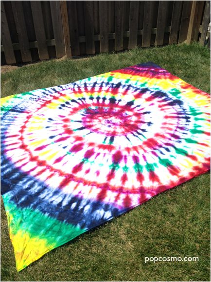 a colorful tie - dyed blanket laying on the grass