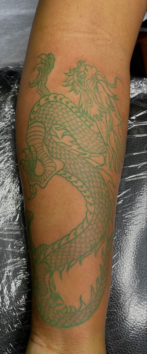 a person with a green dragon tattoo on their leg