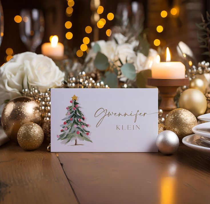 a christmas card sitting on top of a wooden table next to candles and ornaments with lights in the background