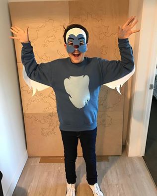 a man wearing a face mask standing on top of a wooden floor