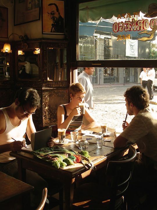 three people sitting at a table in front of a window with food and drinks on it