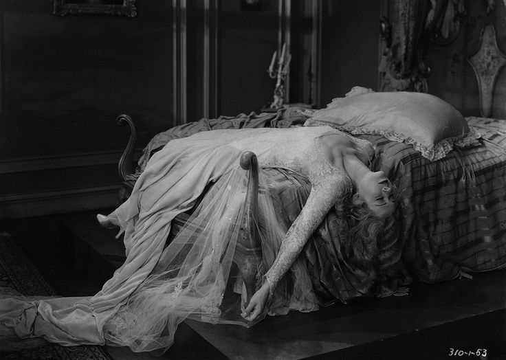 an old black and white photo of a woman laying on a bed with her head down