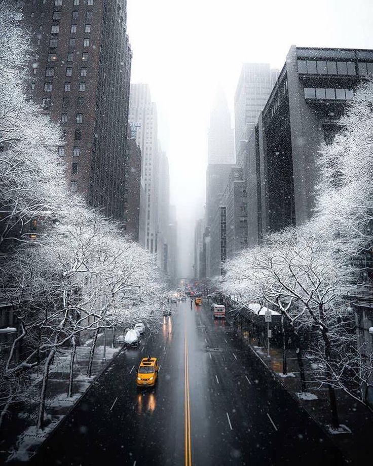 the city street is covered in snow as cars drive down it's side - by - side