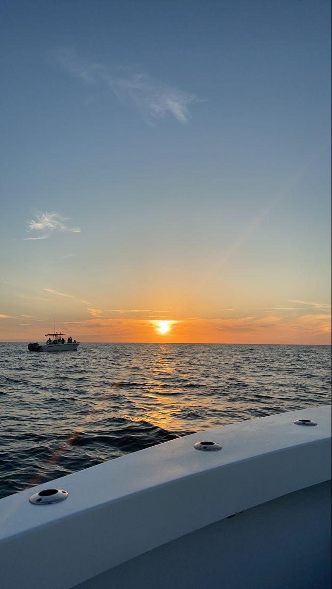 the sun is setting over the ocean on a boat