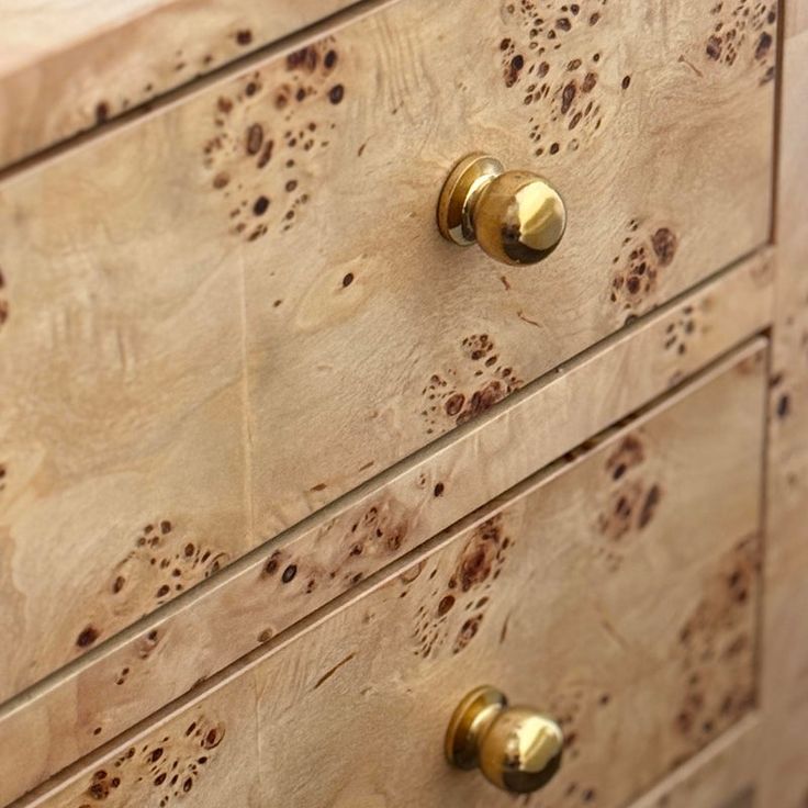 a wooden dresser with brass knobs and brown spots on it's drawer handles