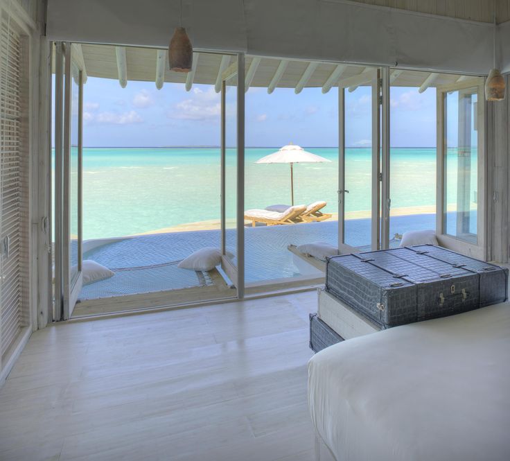 a bedroom with an ocean view is shown in this image, there are two suitcases on the bed