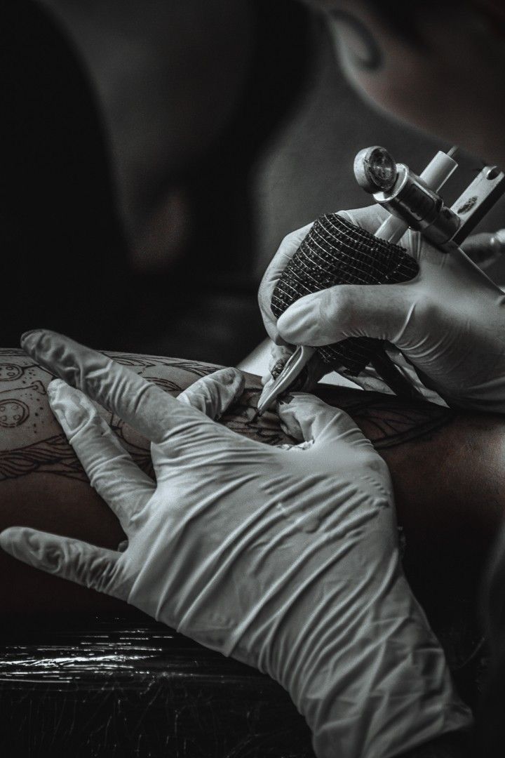 a person getting their arm tattoo done by an artist in white gloves and tattoostands