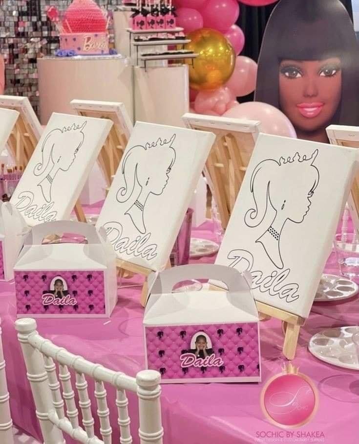 there are many small bags on the table with pink and white decorations behind them, along with balloons