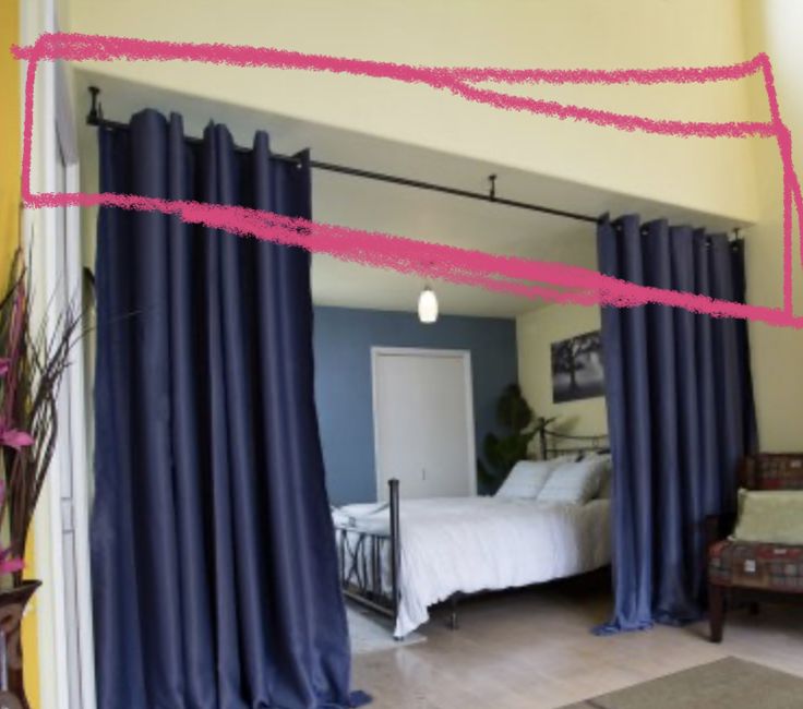 a bedroom with blue curtains and a bed in the background, is seen through a doorway