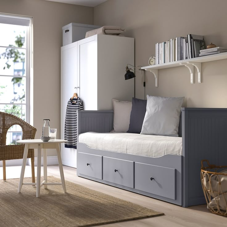 a white daybed sitting in a bedroom next to a window with bookshelves