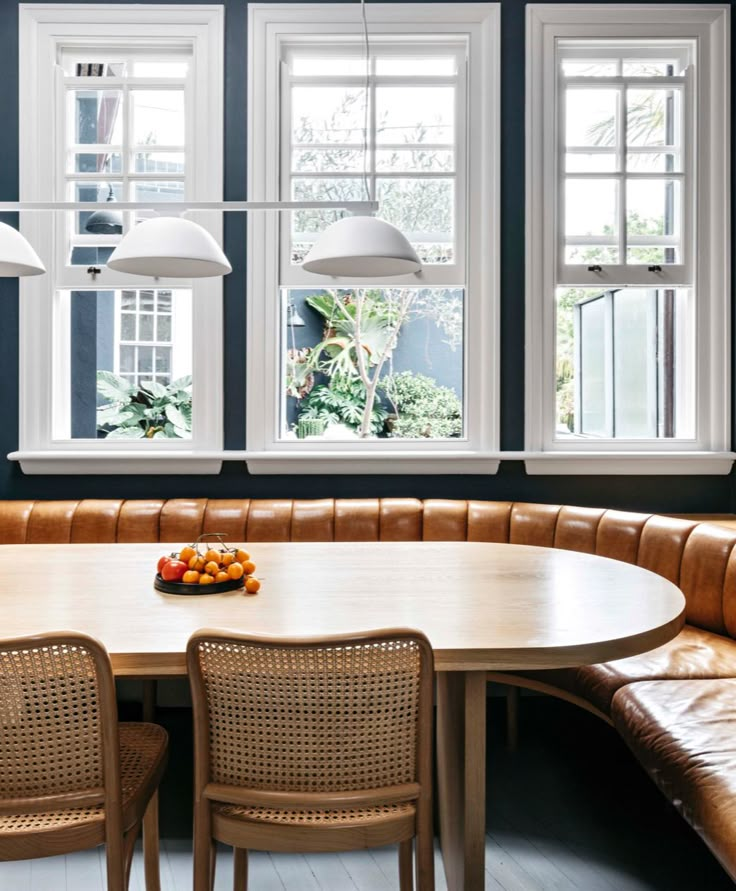 a table with four chairs around it in front of three windows