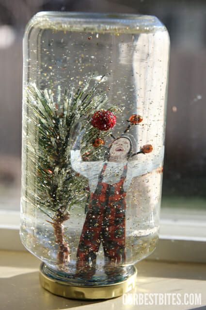 a snow globe with an image of a person holding a christmas tree in it, sitting on a window sill