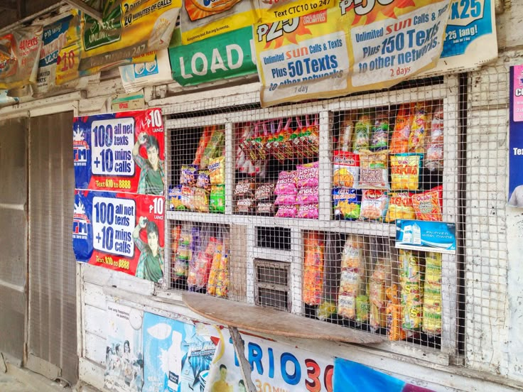 a store front with many different signs on the wall and in baskets hanging from it's sides