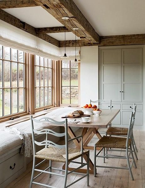 a dining room table and chairs in front of large windows with wooden beams on the ceiling