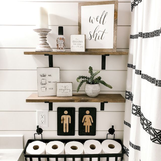 the bathroom is decorated in black and white, with wood shelves above the toilet paper dispenser