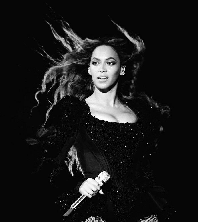 a black and white photo of a woman with long hair holding a microphone in her hand