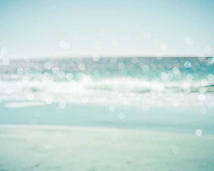 blurry photograph of the ocean and beach with blue sky in the backgroud