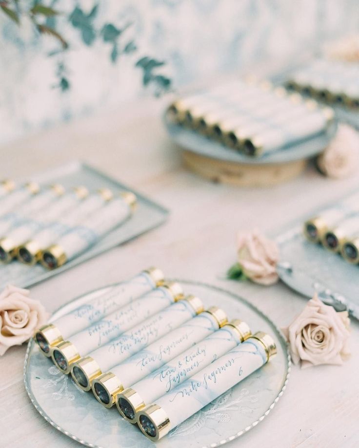 there are many rolled up papers on the table with flowers around them and place settings