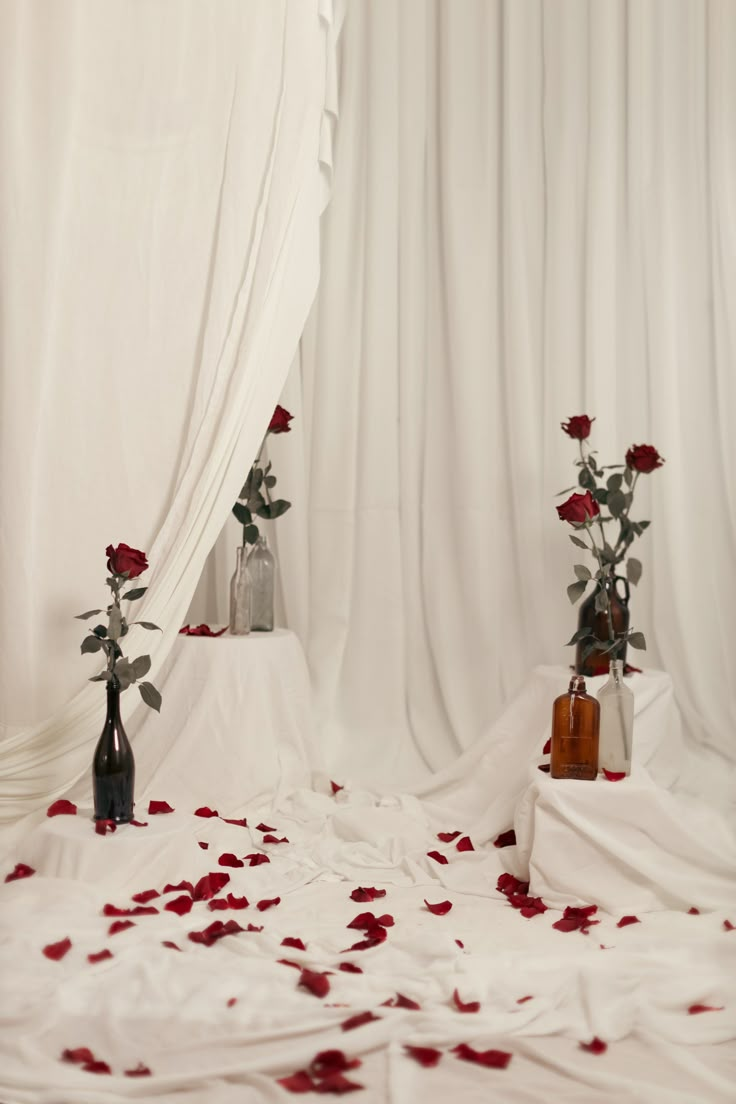 two vases filled with roses sitting on top of a white cloth covered bed sheet