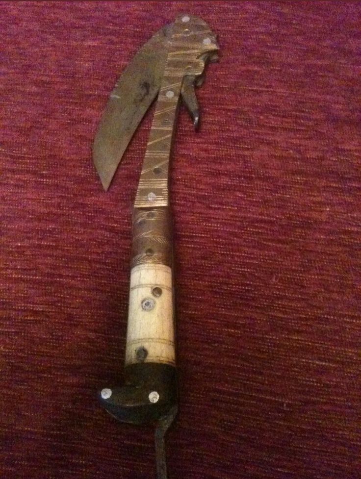 an old knife is laying on top of a red tablecloth with a wooden handle