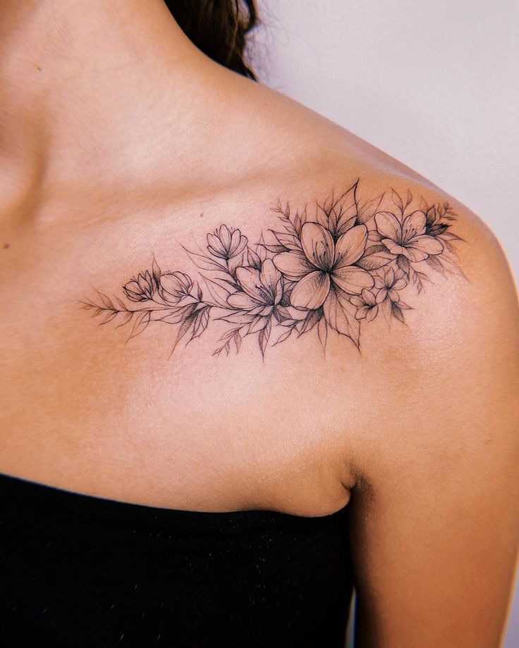 a woman's shoulder with flowers and leaves tattooed on her left side breast area