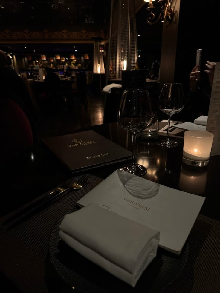 a table with napkins and wine glasses on it in a dimly lit restaurant area