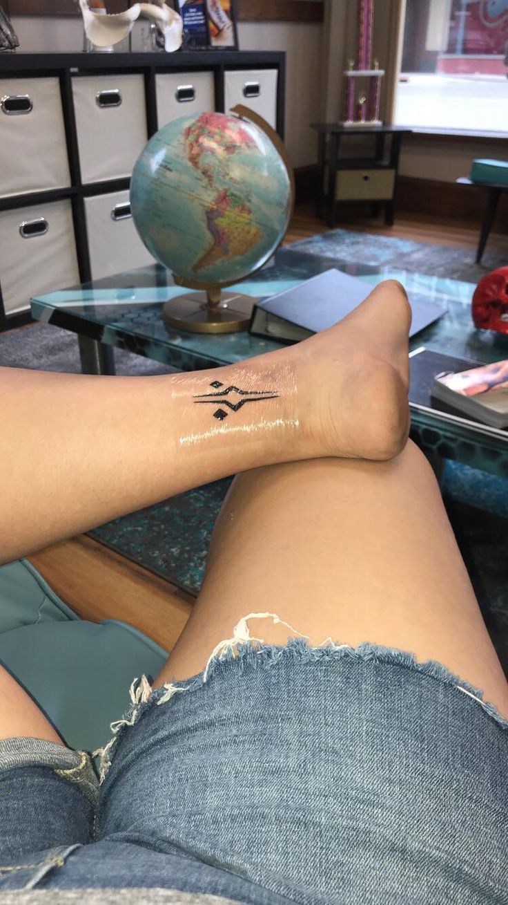 a person with a tattoo on their leg sitting in front of a table and looking at the camera