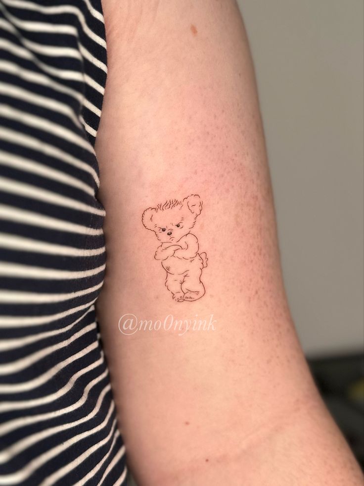 a small teddy bear tattoo on the arm