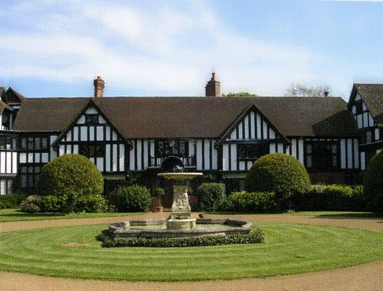 a large black and white house with a fountain in the middle of it's front yard